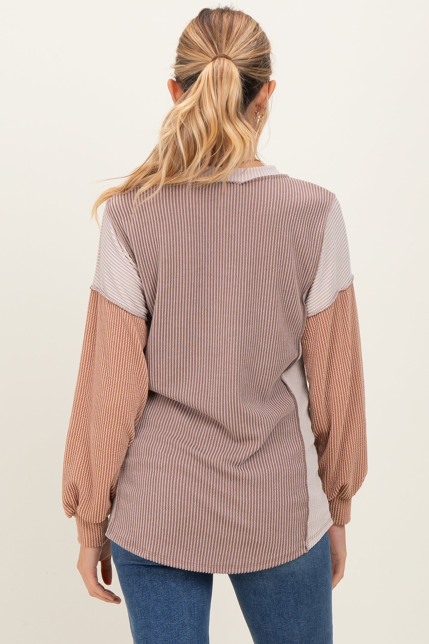 woman wearing a striped maternity top with long sleeves in shades of brown and cream, showing the back view