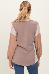 woman wearing a striped maternity top with long sleeves in shades of brown and cream, showing the back view