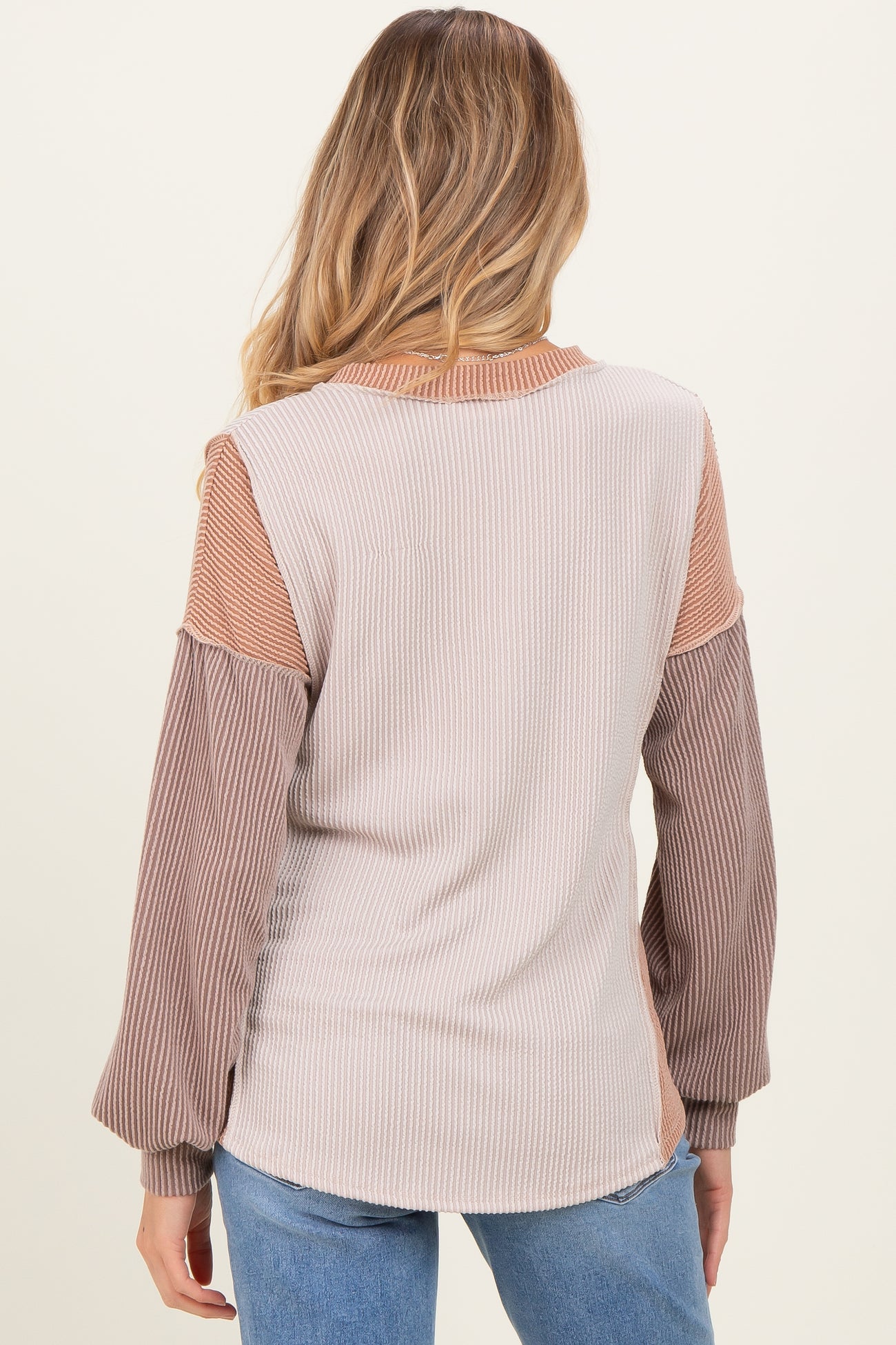 woman wearing a back view of a color-blocked long sleeve maternity top with ribbed texture and balloon sleeves