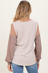 woman wearing a back view of a color-blocked long sleeve maternity top with ribbed texture and balloon sleeves