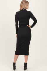 woman wearing a black long sleeve bodycon midi dress, styled with ankle boots, shown from the back