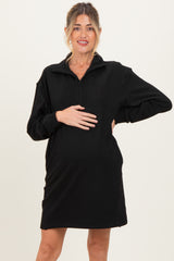 woman wearing a black maternity zip-up dress and holding her baby bump