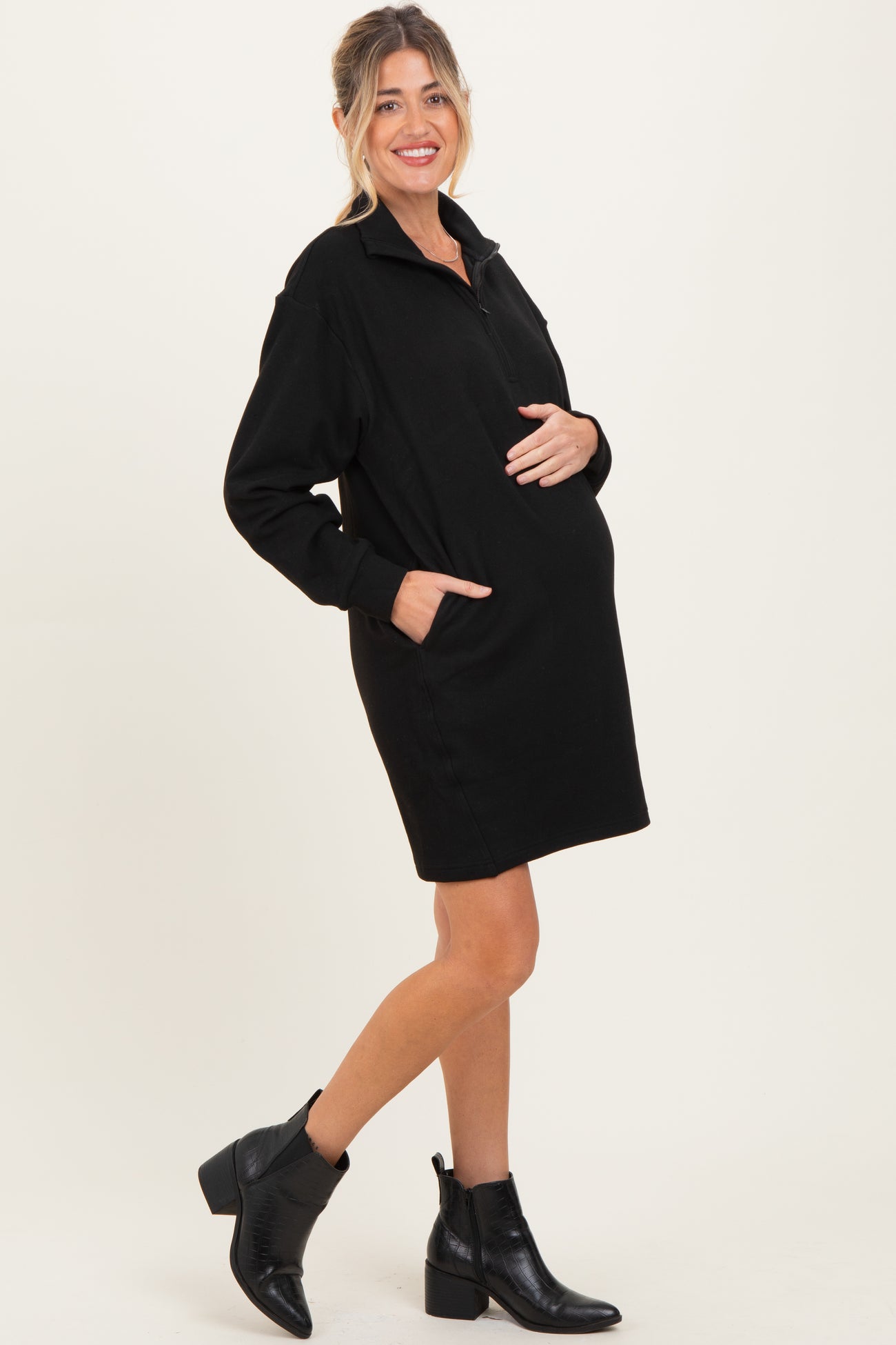 woman wearing a black maternity pullover dress with side pockets and a visible baby bump