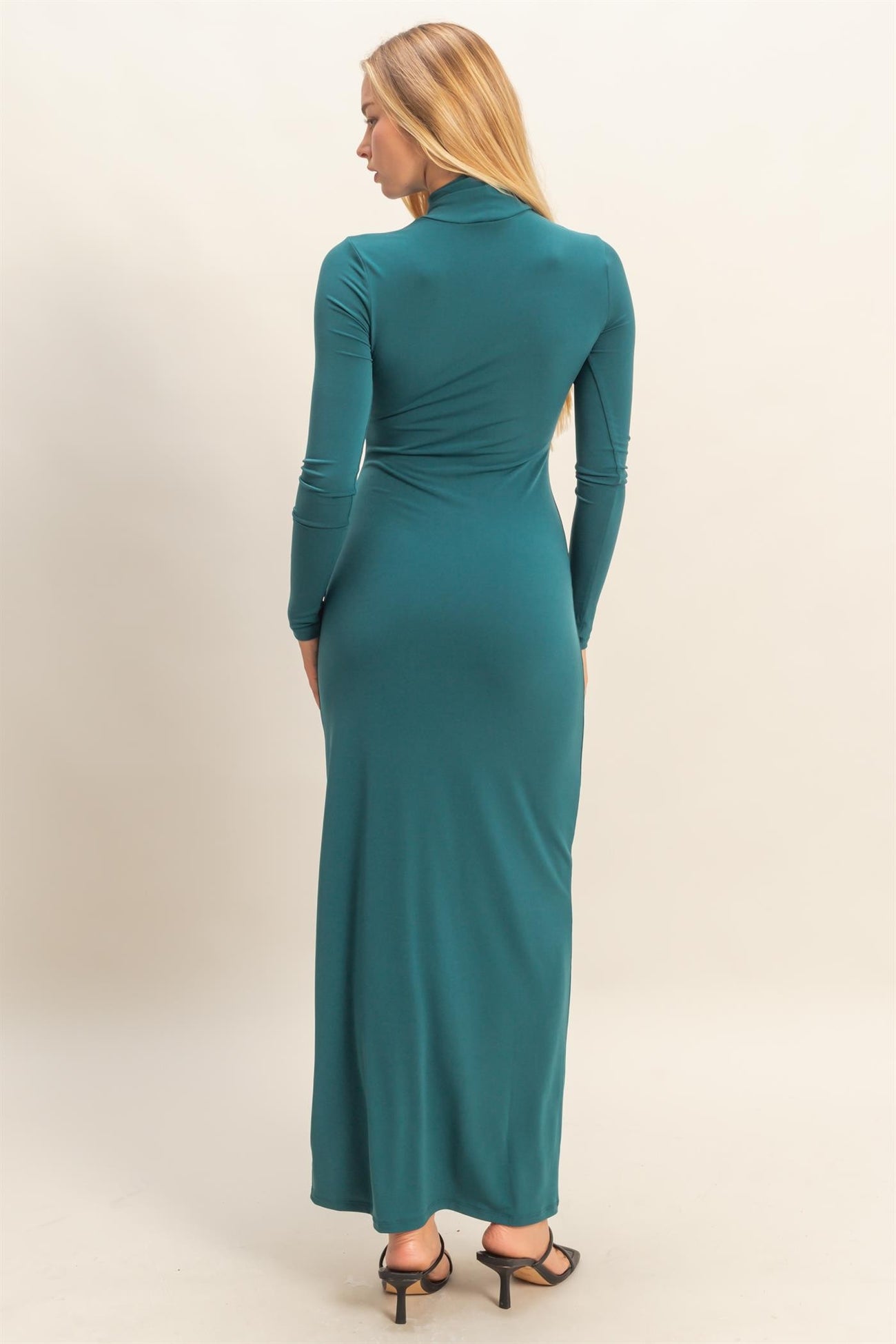 woman wearing a teal long sleeve maxi dress with a fitted silhouette, shown from the back