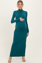 woman wearing a teal long sleeve maternity dress and holding her baby bump