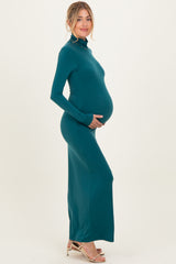 woman wearing a fitted teal maternity maxi dress and holding her baby bump