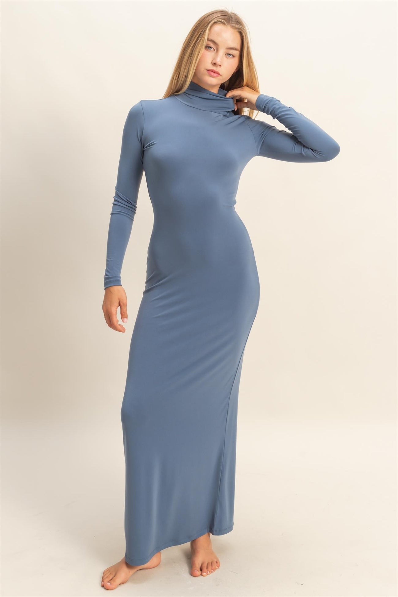 woman wearing a long sleeve blue maxi dress with a high neckline and fitted silhouette