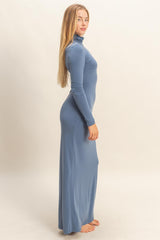 woman wearing a light blue long sleeve turtleneck maxi dress, standing in profile with long hair down