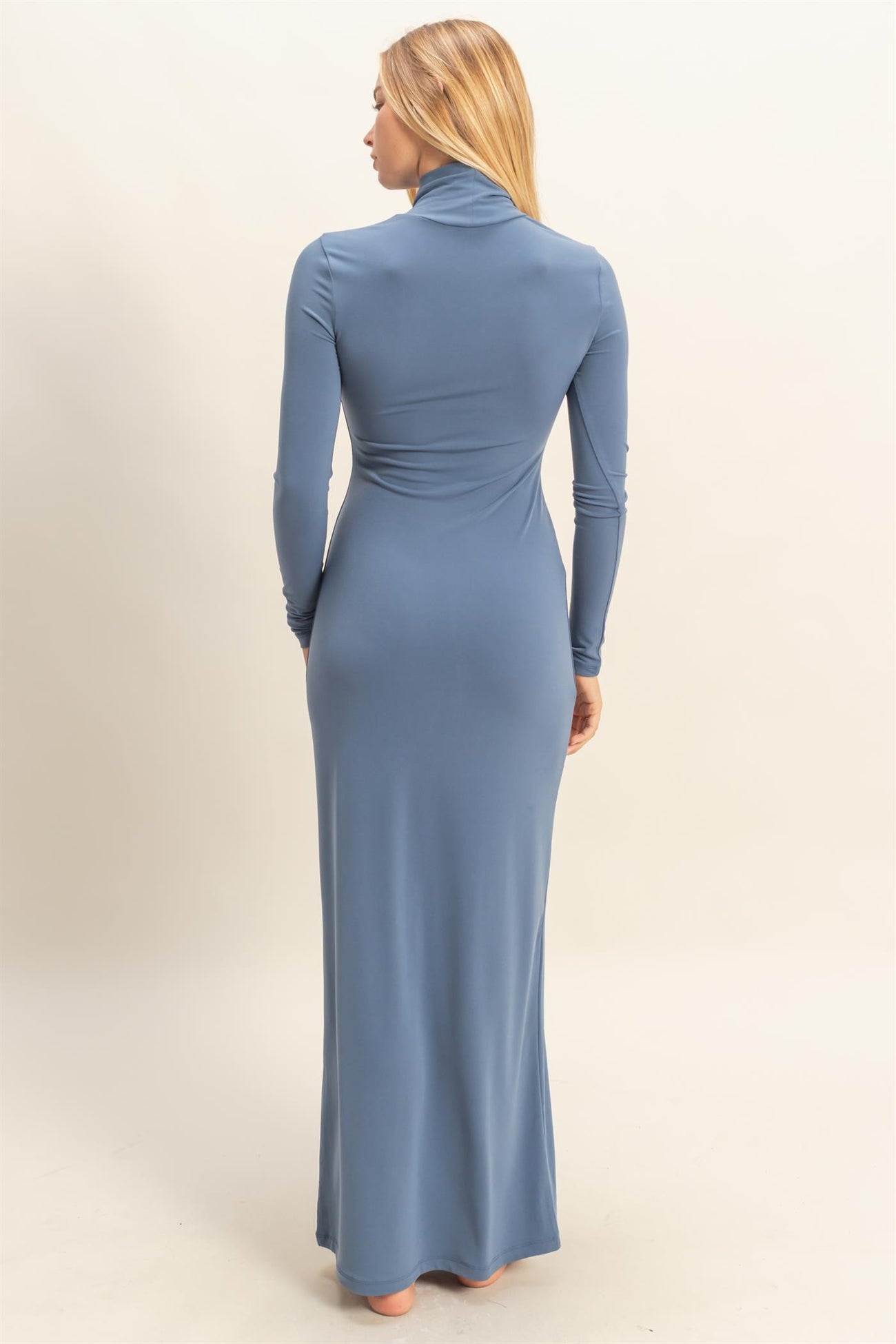 woman wearing a fitted long sleeve blue maxi dress with a high neck from the back