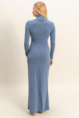 woman wearing a fitted long sleeve blue maxi dress with a high neck from the back