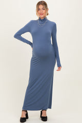 woman wearing a slate blue long sleeve maternity maxi dress with a turtleneck and a visible baby bump