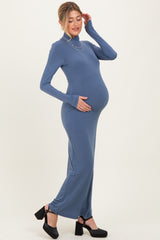 woman wearing a slate blue long sleeve maternity maxi dress and holding her baby bump