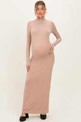 woman wearing a light beige maternity maxi dress with long sleeves and a mock neck, showing her baby bump