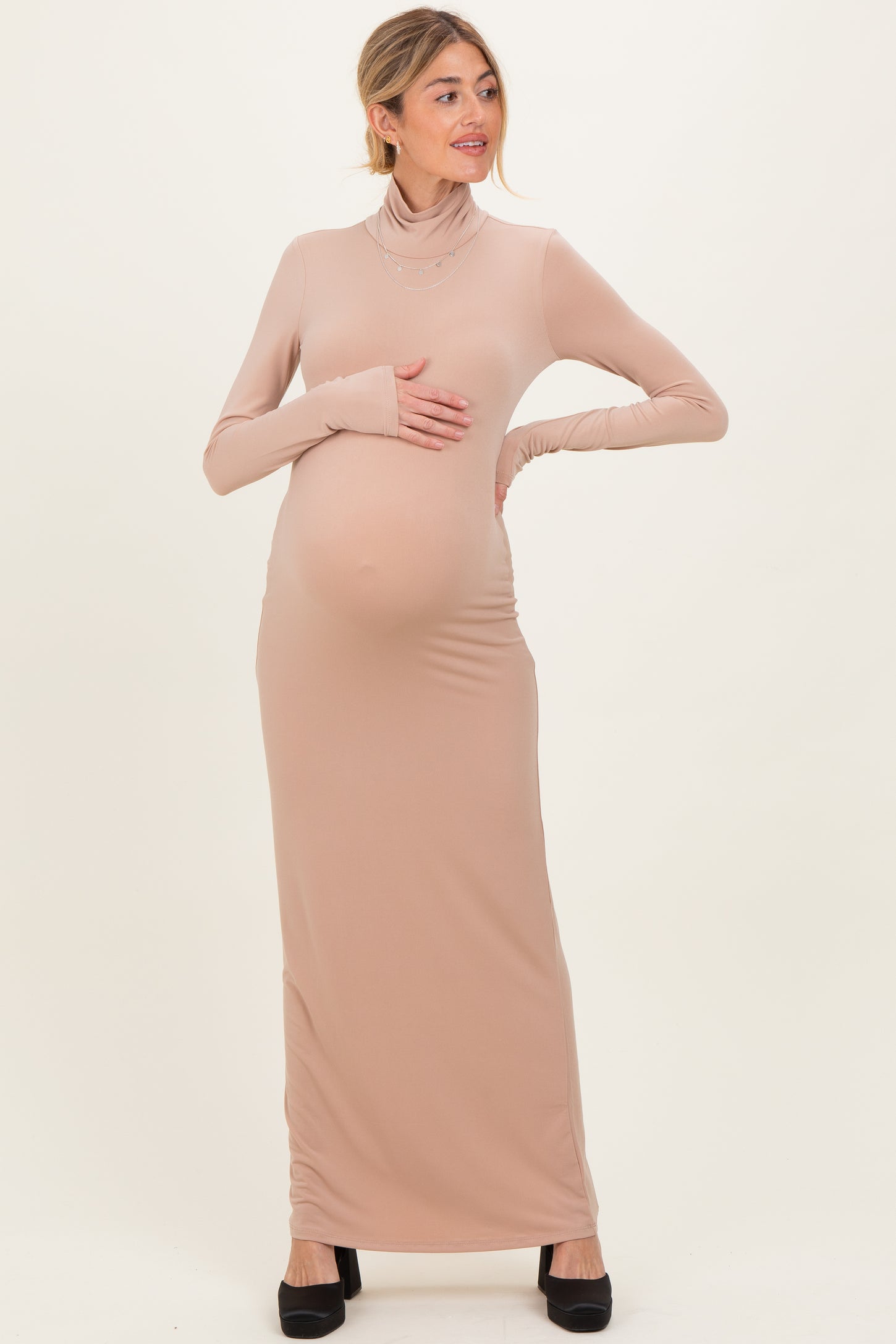 woman wearing a nude long sleeve maternity dress and holding her baby bump