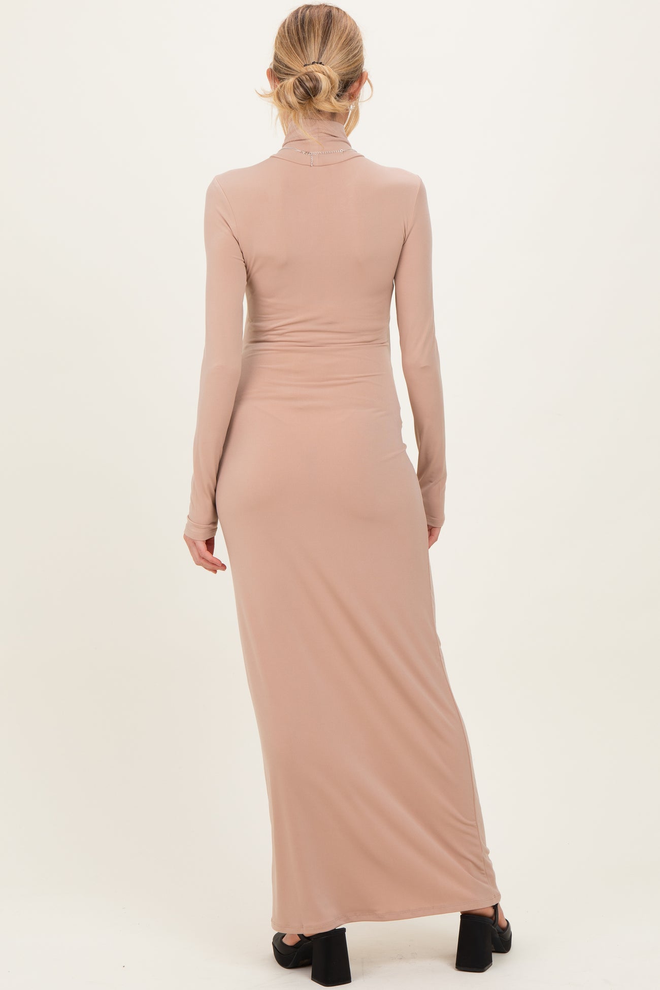 woman wearing a long sleeve beige maternity dress with a fitted silhouette and a floor-length design