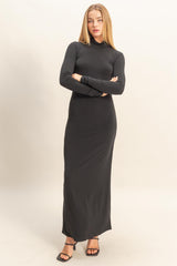woman wearing a fitted black long sleeve maxi dress with a high neck and sleek silhouette