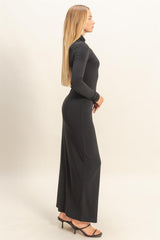 woman wearing a black long sleeve maxi dress with a fitted silhouette and side slit, styled with high heels