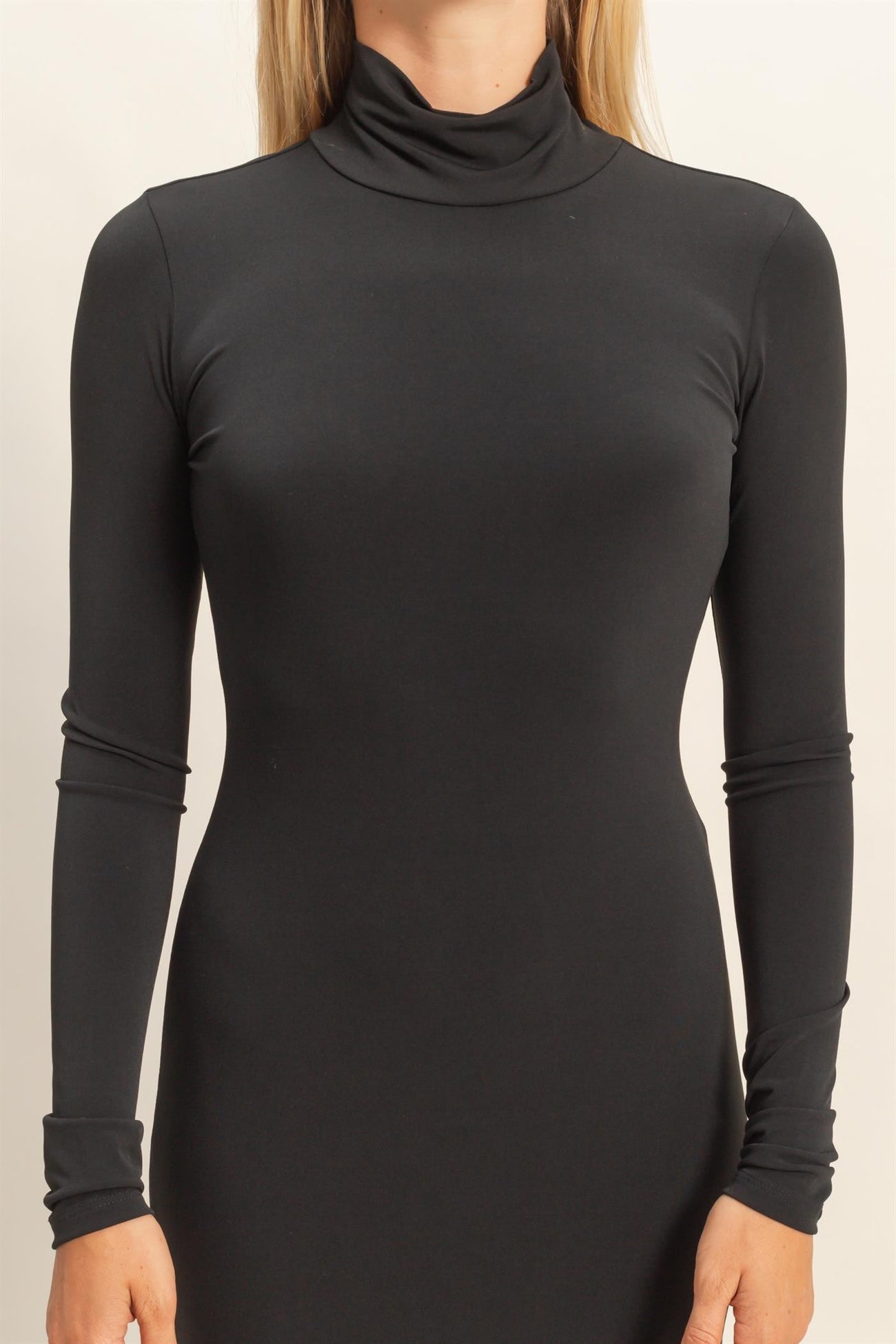 woman wearing a fitted black turtleneck long sleeve dress with a sleek silhouette