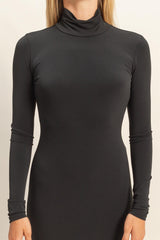 woman wearing a fitted black turtleneck long sleeve dress with a sleek silhouette