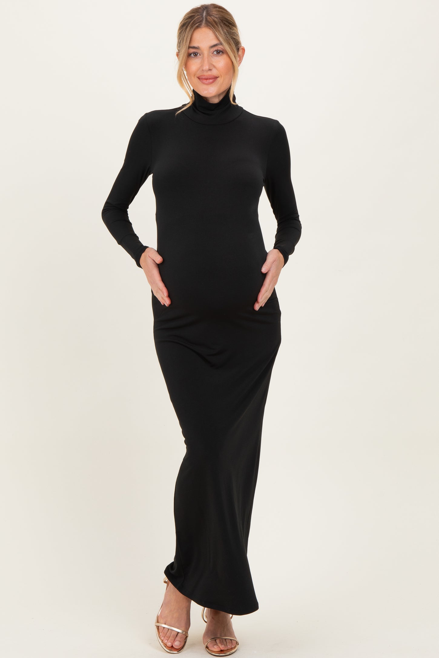 woman wearing a black long sleeve maternity dress, holding her baby bump