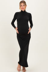 woman wearing a black long sleeve maternity dress, holding her baby bump