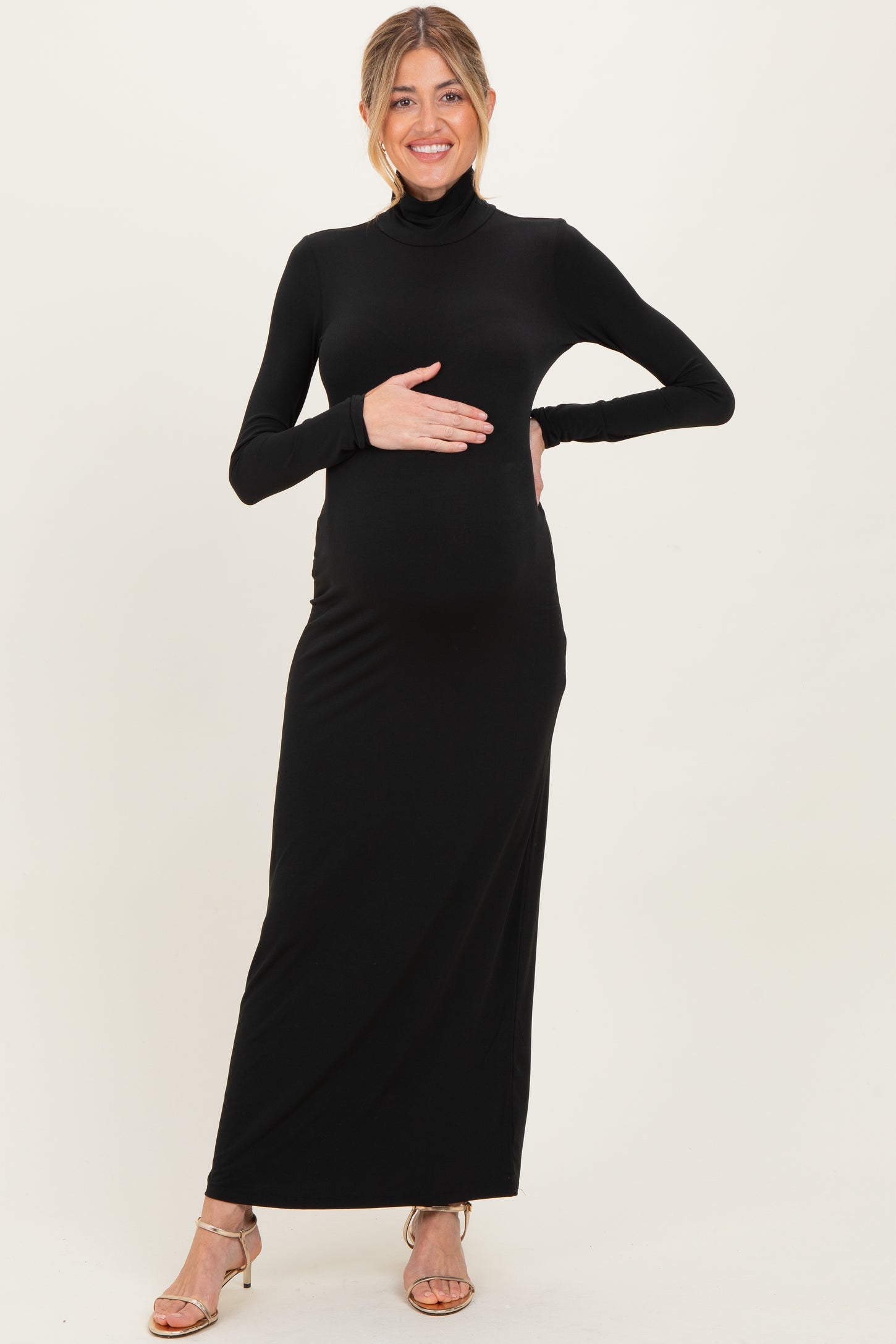 woman wearing a black long sleeve maternity maxi dress and holding her baby bump