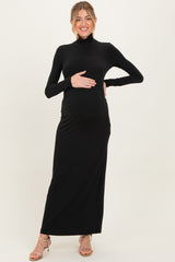 woman wearing a black long sleeve maternity maxi dress and holding her baby bump