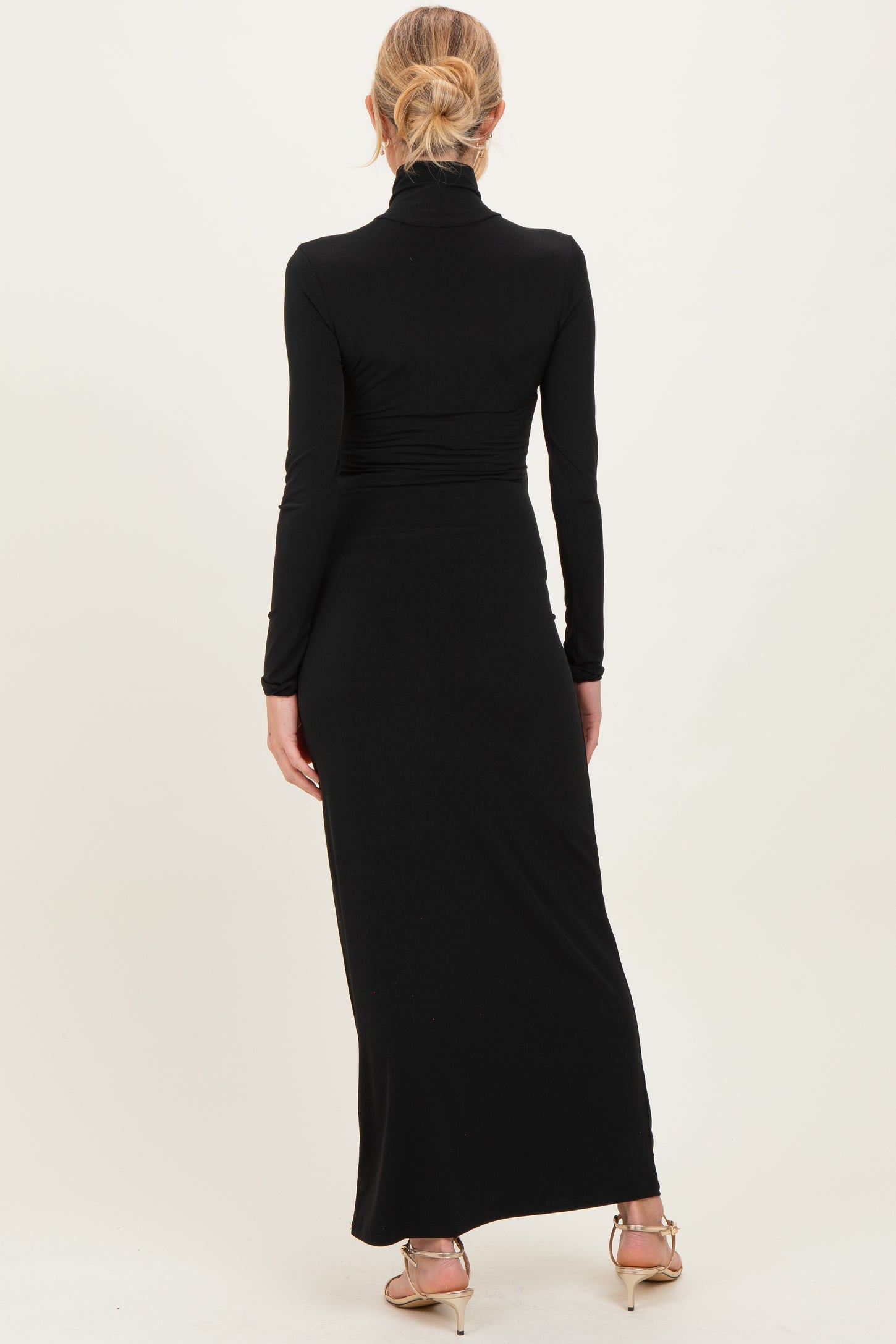 woman wearing a black long sleeve maternity dress with a fitted silhouette and a mock neck