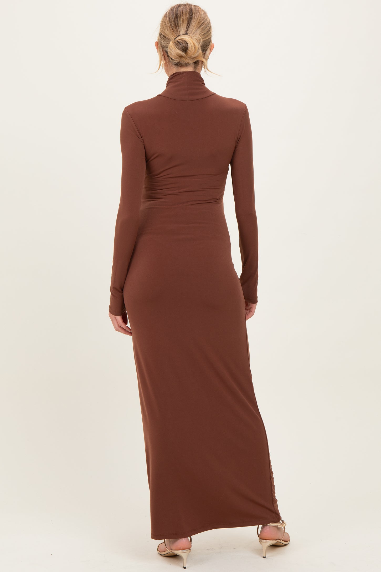 woman wearing a brown long sleeve maternity maxi dress, showing the back view with a fitted silhouette