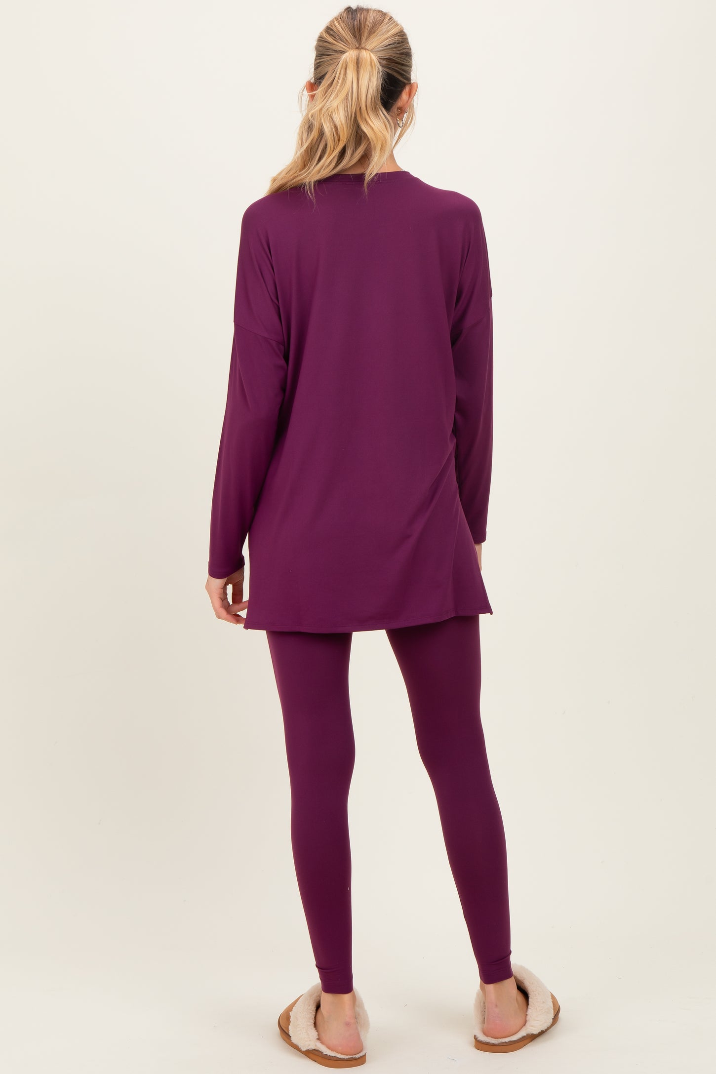 woman wearing a long sleeve purple maternity tunic and matching leggings, facing away with a relaxed style