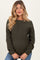 woman wearing an olive green textured maternity sweater with a visible baby bump