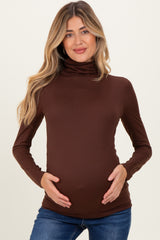 woman wearing a brown long sleeve maternity top and holding her baby bump
