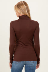 woman wearing a brown long sleeve maternity top with a high neckline and slim fit from the back