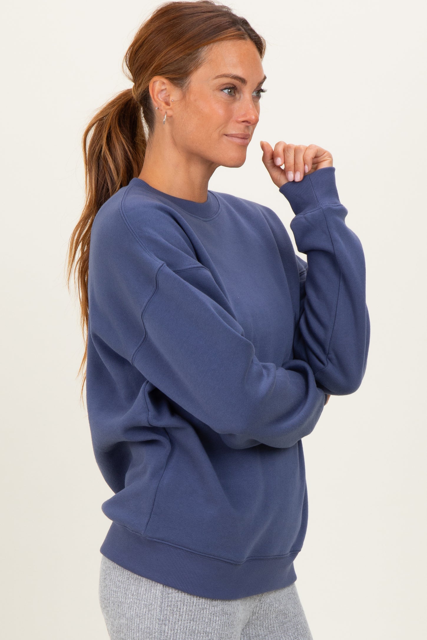 woman wearing a navy blue oversized sweatshirt with long sleeves and a ribbed hem, styled with gray leggings