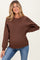 woman wearing a brown maternity sweatshirt paired with blue jeans and showing her baby bump