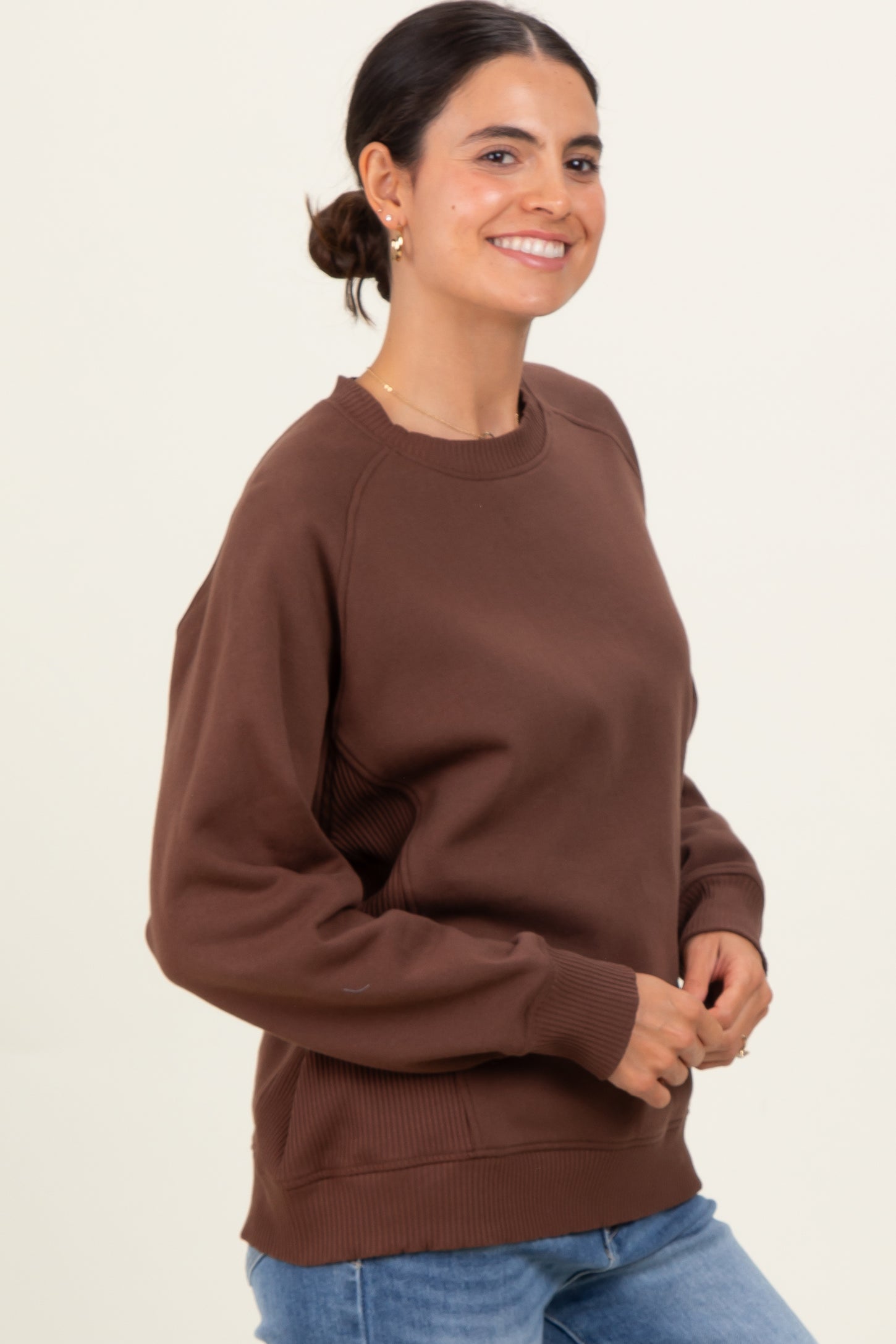 woman wearing a chocolate brown oversized sweatshirt with a relaxed fit and ribbed detailing, smiling at the camera