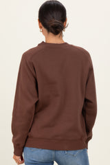 woman wearing a brown oversized sweatshirt with a crew neckline and raglan sleeves