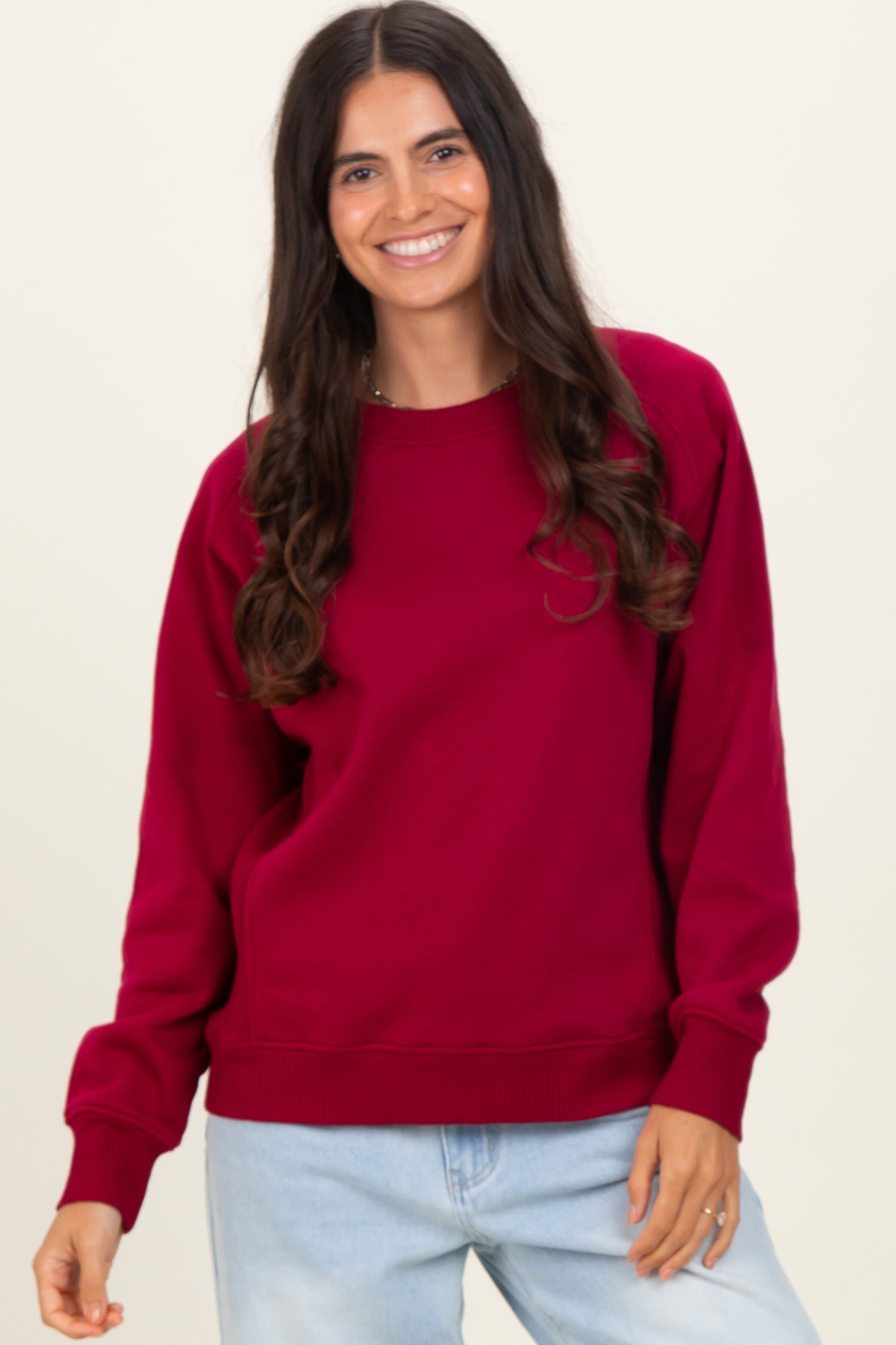 woman wearing a burgundy sweatshirt with a relaxed fit and ribbed cuffs, smiling at the camera