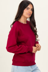 woman wearing a burgundy crewneck sweatshirt with ribbed detailing and relaxed fit