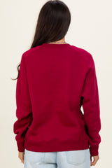 woman wearing a burgundy long sleeve sweatshirt, viewed from the back, with raglan sleeves and ribbed cuffs