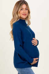 woman wearing a navy blue maternity sweater and holding her baby bump