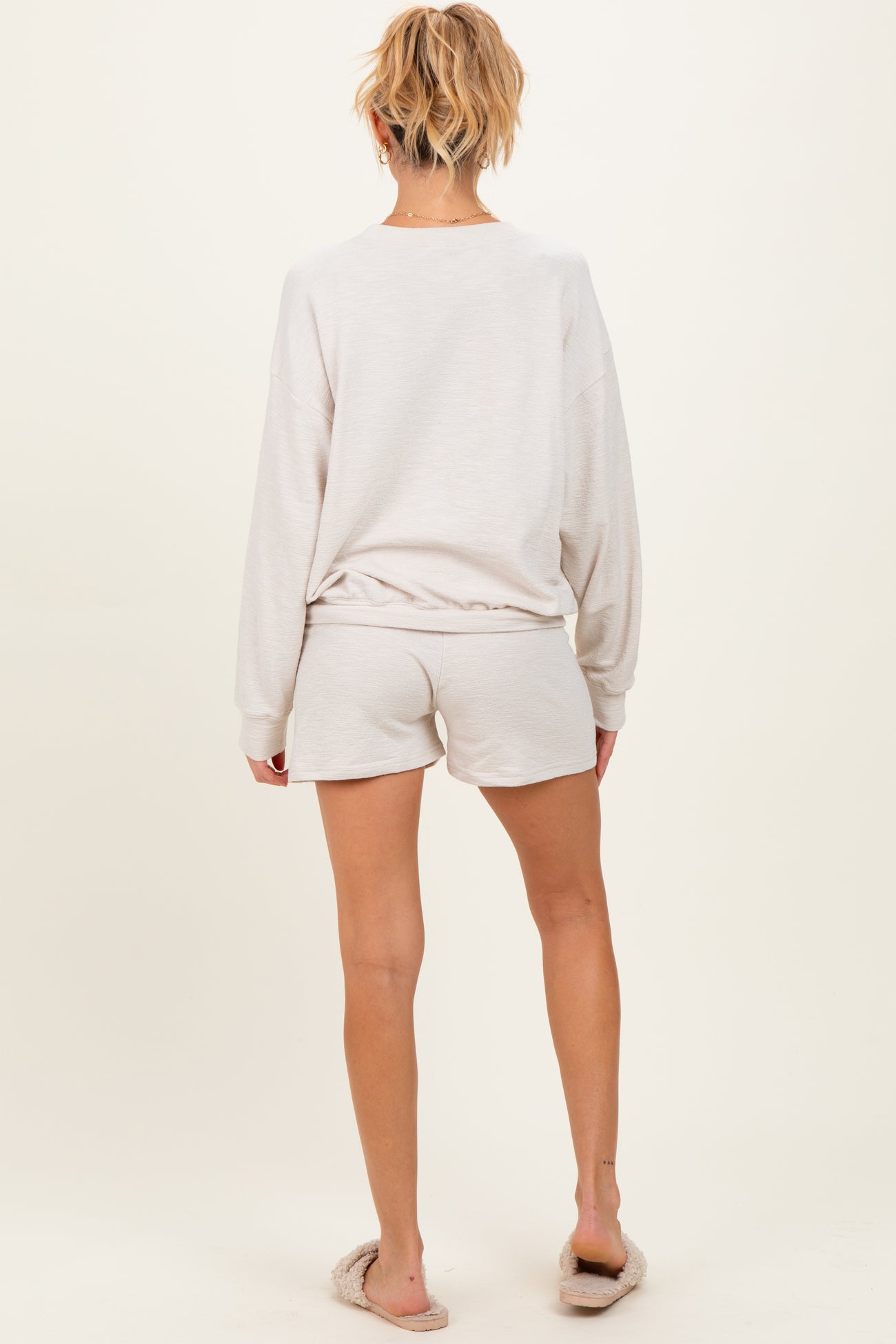 woman wearing a light grey long sleeve maternity top with matching shorts, seen from the back