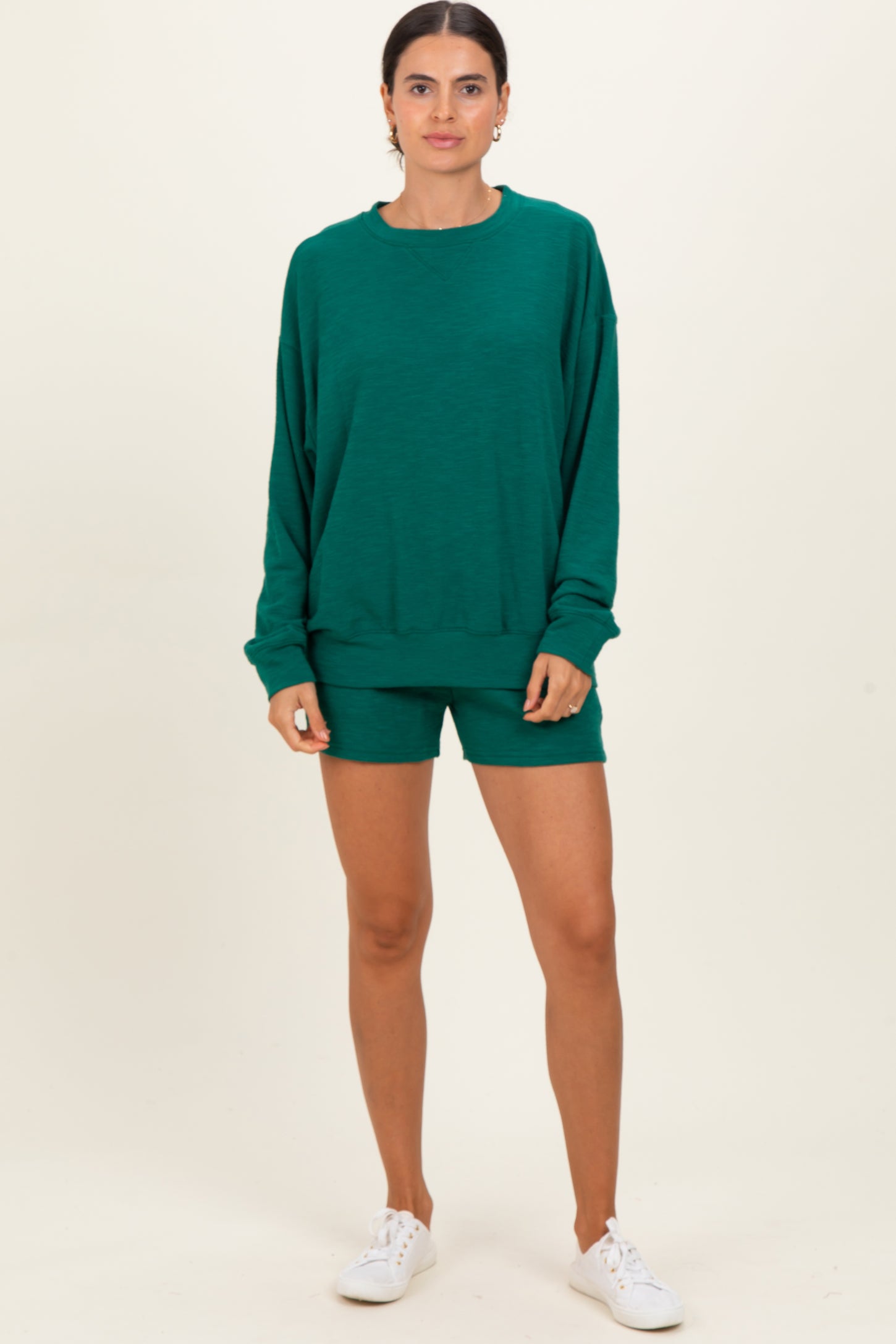 woman wearing a green oversized sweatshirt and matching shorts, styled casually with white sneakers
