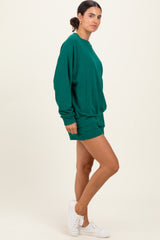 woman wearing a green oversized sweatshirt and matching shorts, styled with white sneakers