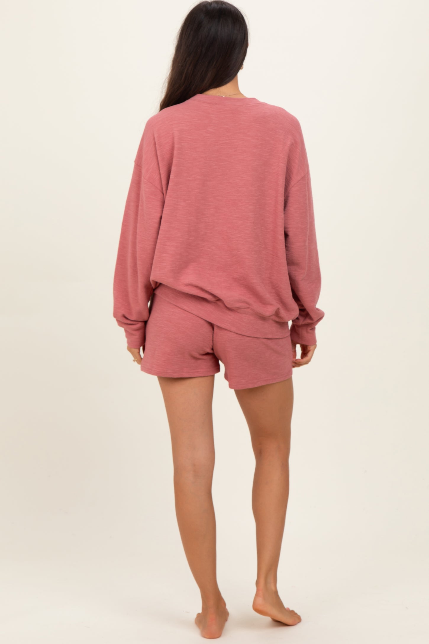woman wearing a dusty rose oversized sweatshirt and matching shorts, viewed from the back