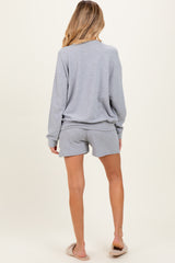 woman wearing a gray maternity long sleeve top and matching shorts, seen from the back