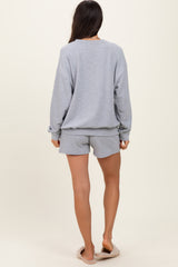 woman wearing a light grey oversized sweatshirt and matching shorts, viewed from the back