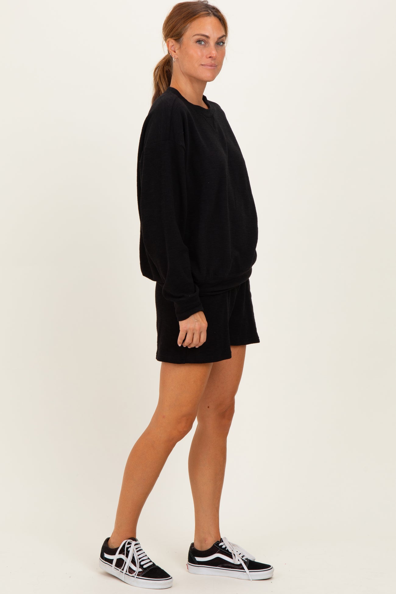 woman wearing a black oversized sweatshirt and matching black shorts with black sneakers