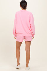 woman wearing a pink oversized sweatshirt and matching shorts, seen from the back