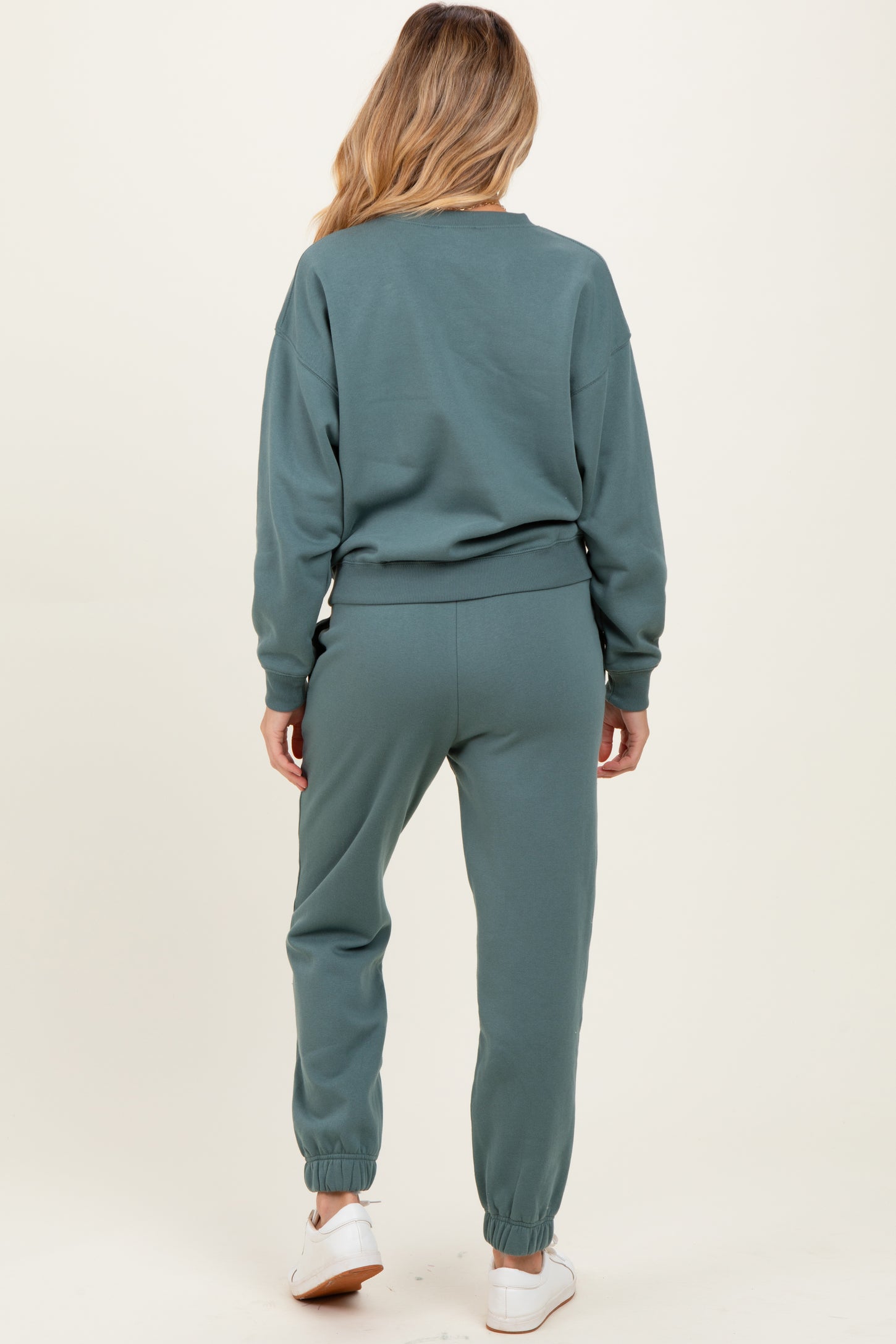 woman wearing a soft green maternity sweat suit with relaxed fit and elastic ankle cuffs, showing her baby bump from the back